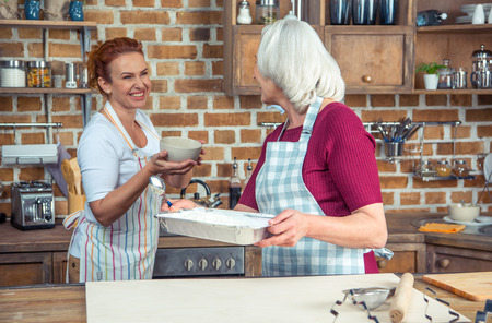 Two women preparing ingredients for baking in kitchenの写真素材