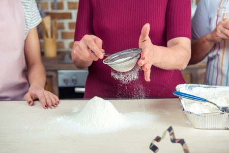 Partial view of woman sifting flour on tableの写真素材