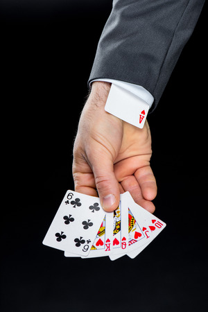 Partial view of man holding playing cards with hidden in sleeve ace of hearts
