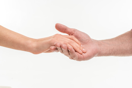 Close-up view of male hand carefully holding female hand on whiteの写真素材