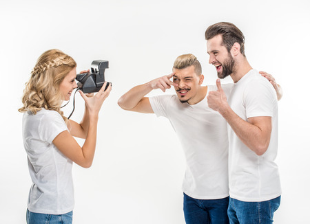 Happy young friends making photos on white
