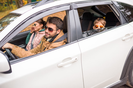 Happy friendly family travelling by car on rural road