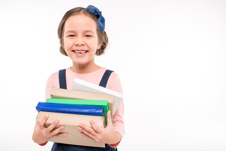 Smiling schoolgirl holding books on white