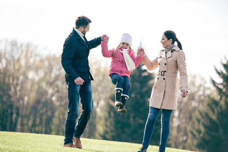 Happy family holding hands and walking in park at sunny autumn dayの写真素材