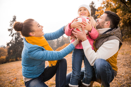 Happy family playing with ball in autumn park