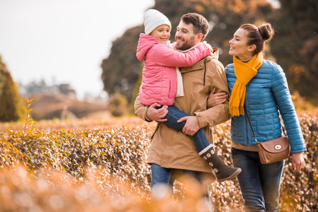 Happy family with one child walking in beautiful autumn park