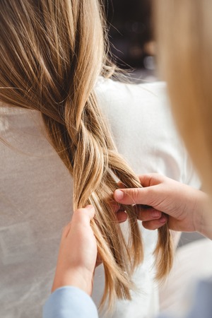 Close-up partial view of little daughter plaiting braid of her motherの写真素材
