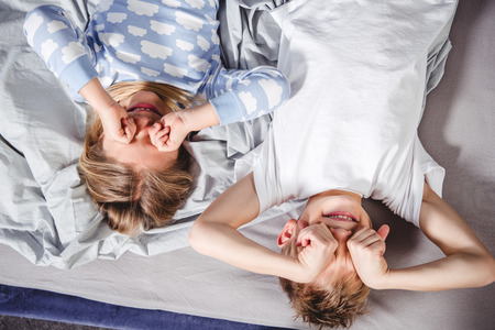 Top view of cute little brother and sister waking up in bedの写真素材