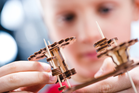 Close-up view of kid holding wooden gear mechanical toyの写真素材
