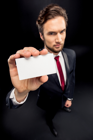 Handsome businessman showing blank card on blackの写真素材