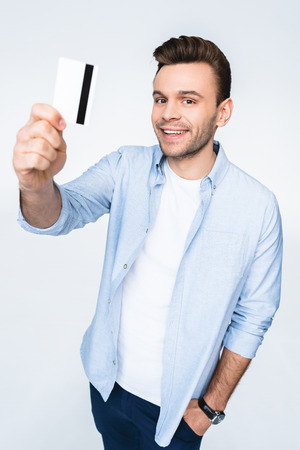 man holding credit card and smiling at cameraの写真素材