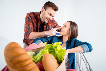 couple with shopping cart and grocery bag on whiteの写真素材