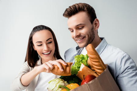 man looking at grocery bag and smiling woman holding baguetteの写真素材