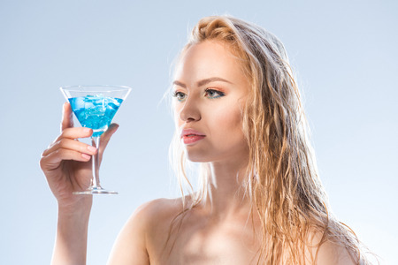 woman looking at cocktail drink in hand on whiteの写真素材