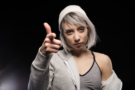 woman in sports clothing pointing at camera on black