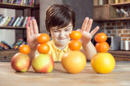 little boy playing with fresh fruits on wooden tableの写真素材