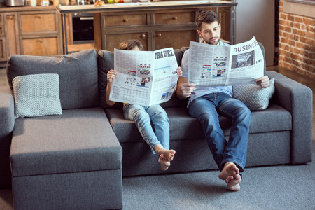 father and son sitting on couch and readingの写真素材