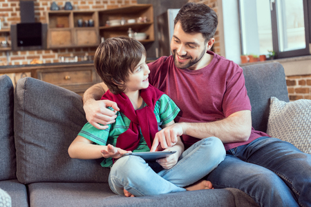 father and son using digital tablet at homeの写真素材