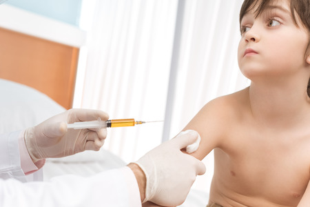 doctor making injection to little boy in hospitalの写真素材