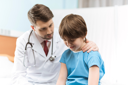 portrait of doctor cheering up little crying boyの写真素材