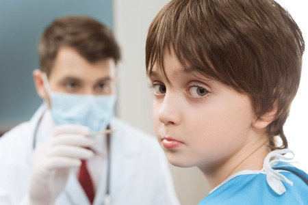 boy looking at camera while doctor goingの写真素材