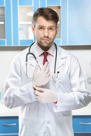 serious doctor in medical uniform and gloves in labの写真素材
