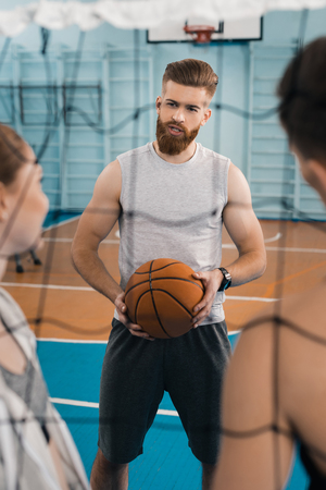 young sportsman with ball talking with teammates in sports hallの写真素材