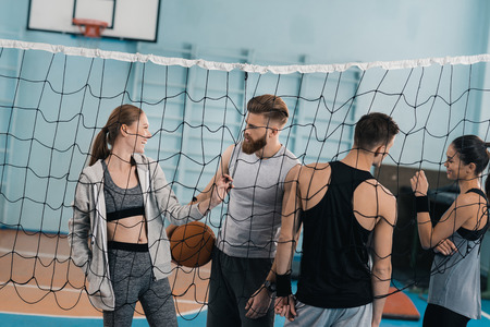 young people with ball standing near net in sports hallの写真素材