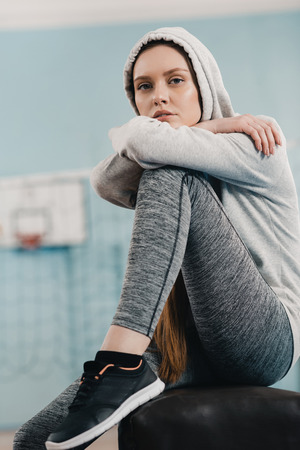 sporty woman sitting on pommel horse and looking at cameraの写真素材