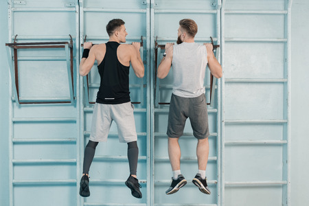 sporty men exercising on sport equipment in gym