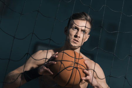 concentrated sporty man holding basketball ball in handsの写真素材