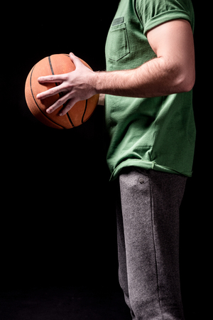 partial side view of man holding basketball ball in hands