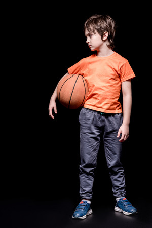 serious boy holding basketball ball and looking awayの写真素材