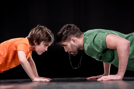 side view of man with whistle and boy doing push ups and looking at each otherの写真素材