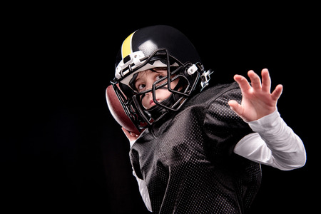 Little boy american football player in uniform throwing ballの写真素材