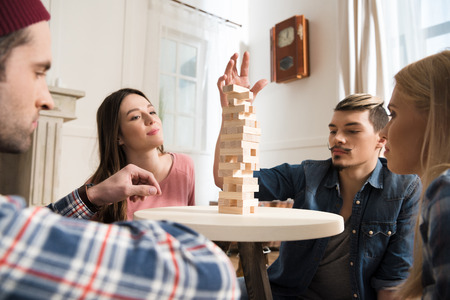 men and women playing jenga game at home