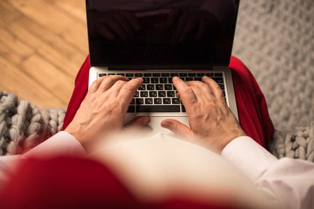 Hands of Santa Claus typing on laptopの写真素材