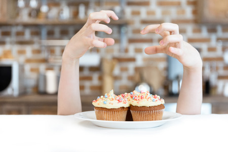 little girl and tasty cupcakes on plateの写真素材