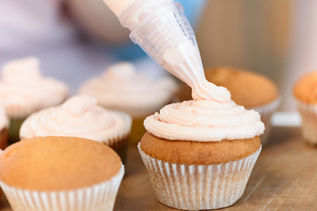 putting cream on cupcakes processの写真素材