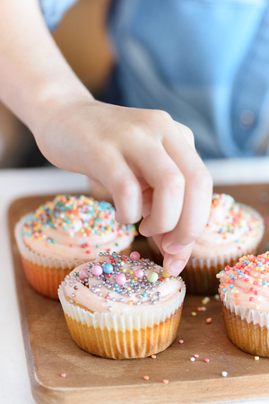 girls hand decorating cupcakes with confettiの写真素材