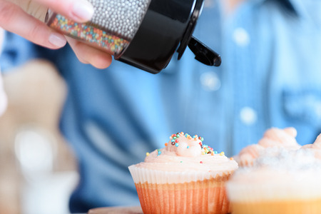 woman decorating cupcakes with confettiの写真素材