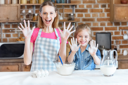 smiling mother and daughter showing hands in flourの写真素材