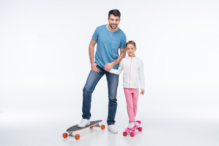 father and daughter standing with skateboards on whiteの写真素材