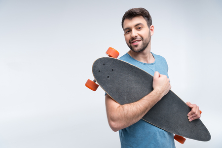 portrait of smiling man holding skateboard in handsの写真素材