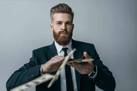stylish businessman throwing dollar banknotes on greyの写真素材