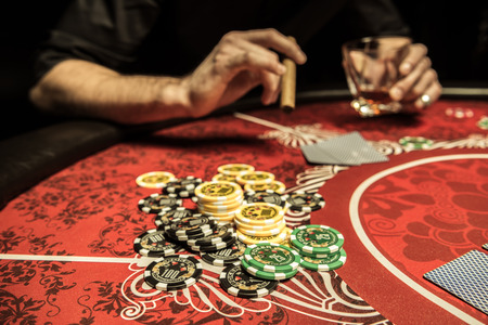 poker chips on table near player with glass and cigar