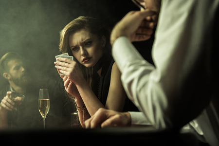 concentrated woman playing poker with cards in handsの写真素材