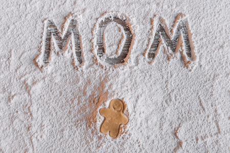 'Top view of uncooked gingerbread man and word mom written in flour, Mothers day conceptの写真素材