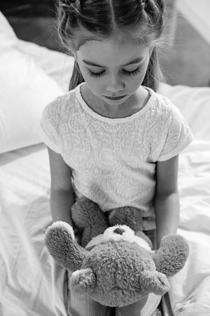 upset girl with teddy bear in hospital chamberの写真素材