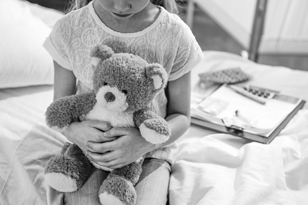 girl with teddy bear in hospital chamber, black and white photoの写真素材